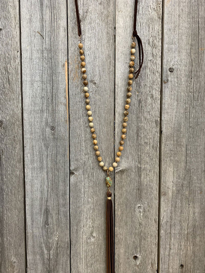 This is an image of J.Forks Designs 32" Picture Jasper and Chocolate Leather Necklace with Turquoise and Tassel Drop laying on a vintage wood background. This photograph was taken at the J.Forks Designs studio on Main Street in Boerne, Texas. 