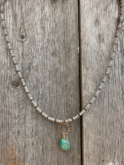 J.Forks Designs necklace hanging on a wooden backdrop. This necklace is 16" with small Austrian crystal and turquoise drop.