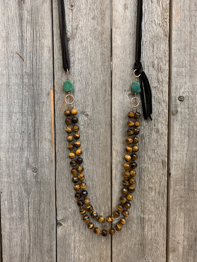 J.Forks Designs necklace hanging on wooden backdrop. This is a 2 strand, 32" Faceted Tigers Eye necklace with Kingman Turquoise sides and chocolate leather back.