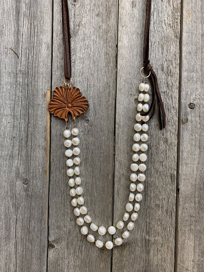 This is an image of the J.Forks Designs Freshwater Pearls Necklace with Sheridan Side Pendant hanging on a vintage wooden backdrop. This image was taken in the J.Forks Designs studio located in Boerne, Texas. Just outside of San Antonio.